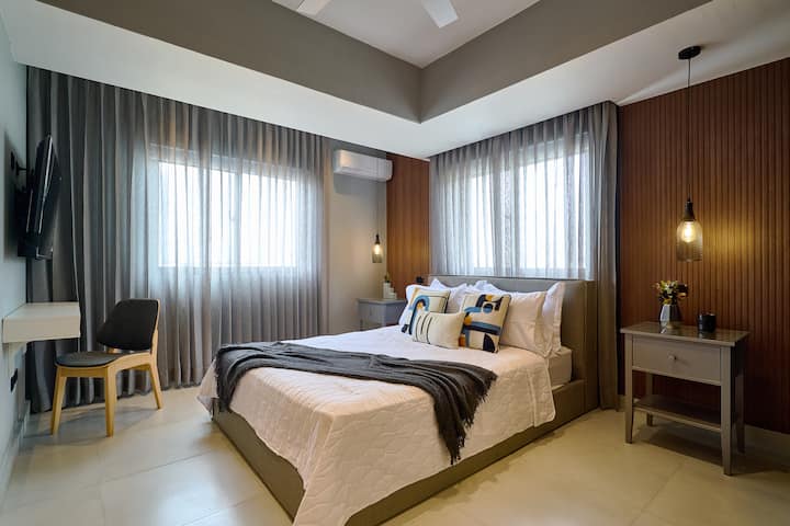 ห้องนอนที่ 2 ที่น่าทึ่งมาพร้อมกับเตียงควีนไซส์หรูหราฟูกนอนระดับไฮเอนด์แอร์พัดลมเพดานม่านทึบแสงไฟโดยรอบตู้เสื้อผ้ากว้างขวางสมาร์ททีวีโต๊ะทำงานวิวเมืองที่สวยงามและห้องน้ำในตัวสุดหรูพร้อมฝักบัวอาบน้ำแบบสายฝน