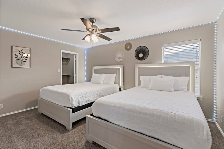 モダンな寝室には、ヘッドボードに照明付きのクイーンサイズベッド2台、快適な寝具、環境LEDアクセントが備わっています。 おしゃれな壁のインテリアと自然光が、お友達やご家族とのリラックスした滞在に最適なシックな空間です。