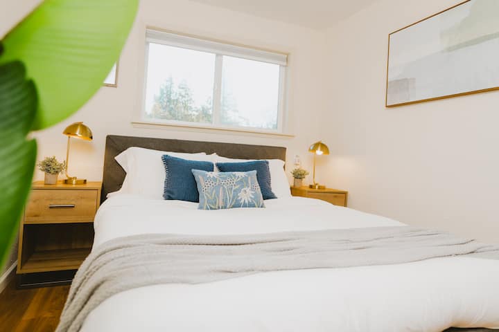 Wake up to natural light in this bright and cozy guest room, featuring a plush bed and views of the surrounding Pacific Northwest greenery.