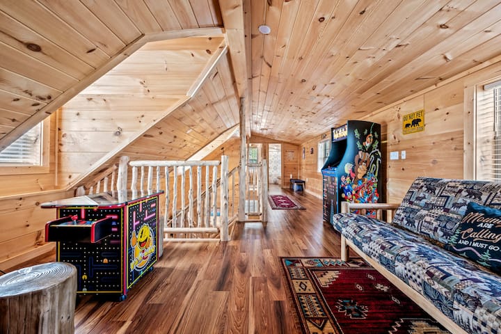 The game room has a sleeping futon, board games, a cocktail arcade game and standing arcade game. 