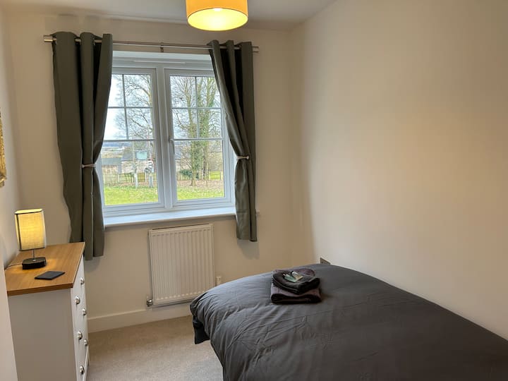 Chumba kimoja cha kulala kilicho na kifua cha droo na reli inayoning 'inia