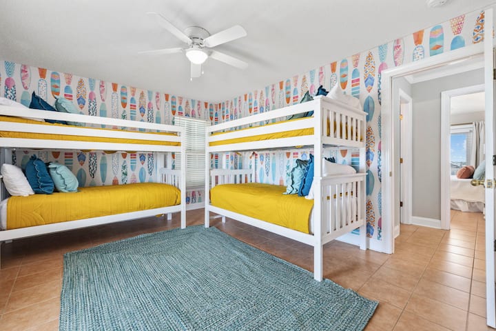 Surf’s up even when you're sleeping!  This cozy, beach-themed room features two sturdy bunk beds, comfortably sleeping four guests. The playful surfboard wallpaper adds a splash of coastal charm. 