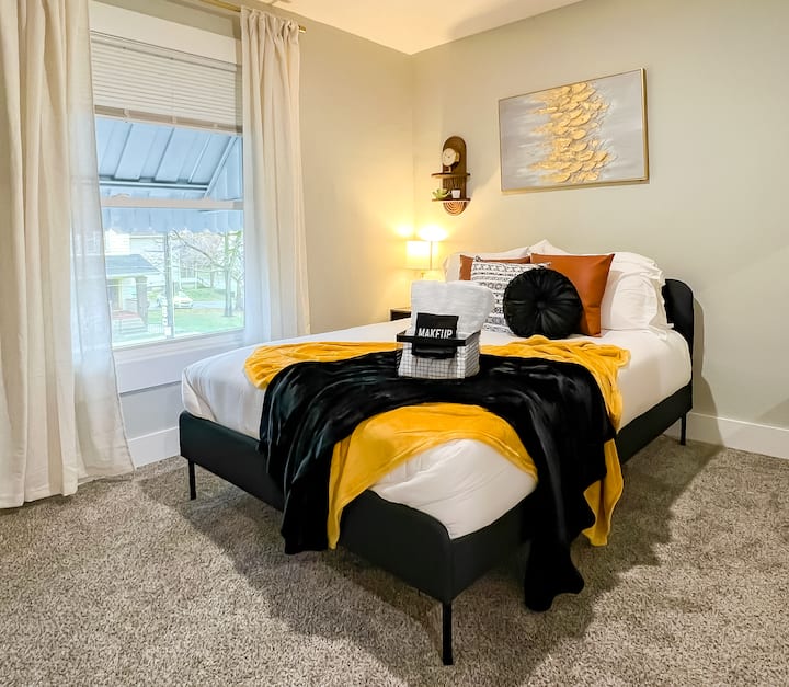 Bienvenido a la habitación negra y dorada: una acogedora cama tamaño queen está vestida con sábanas de lujo, lo que garantiza un sueño reparador. Una mesa auxiliar, una máquina de sonido y una lámpara proporcionan iluminación adicional y el paisaje sonoro perfecto para dormir. También encontrarás un pequeño tocador / escritorio. 