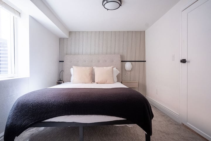 חדר שינה מס '4 מציע מקום מפלט שקט במרתף עם מיטה נוחה, קיר מבטא מודרני ותאורה רכה — מושלם לשינה נינוחה בחלל קריר ושלו.