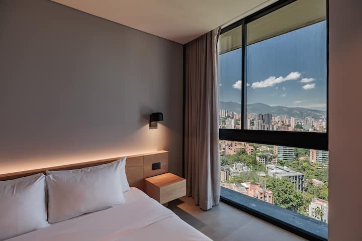 Furahia kitanda chenye starehe na mandhari nzuri ya milima na kijani kibichi cha Medellín kupitia dirisha lake kubwa. Ukiwa na dawati la kazi, bafu la kujitegemea, kiyoyozi, Televisheni mahiri na sehemu yote ya kujisikia nyumbani.