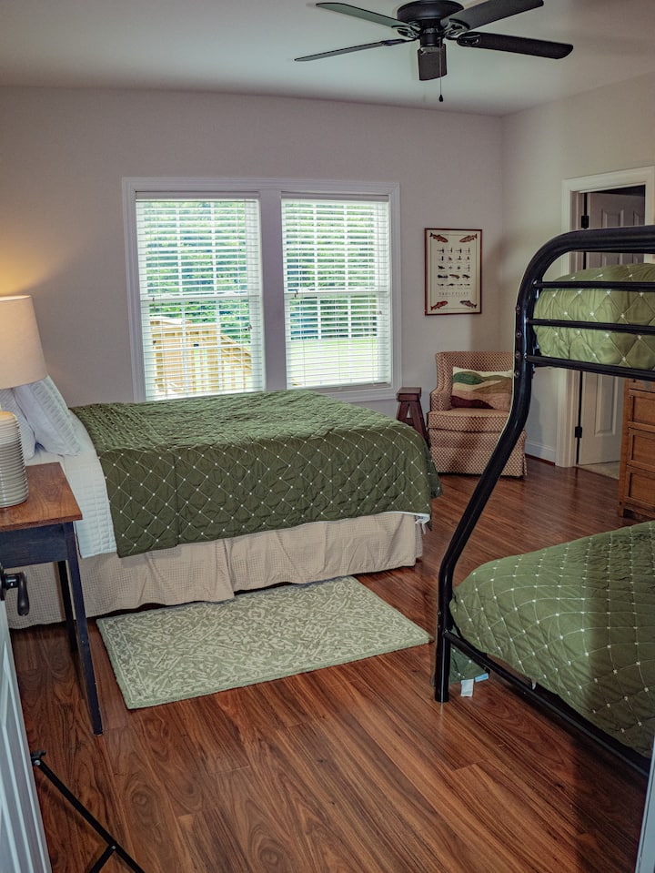 Bedroom with walk-in closet and plenty of storage for guest luggage. Bedroom holds a small chest of drawers. Bedroom has a queen bed and bunkbed with full and twin sized beds. Bunkbeds have outlets in reach with night lamps.