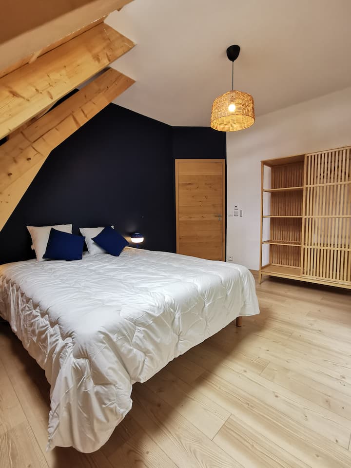 חדר כחול עם מיטת קווין סייז המשקיפה על היער. יש ארונות ומתקני אחסון שונים.