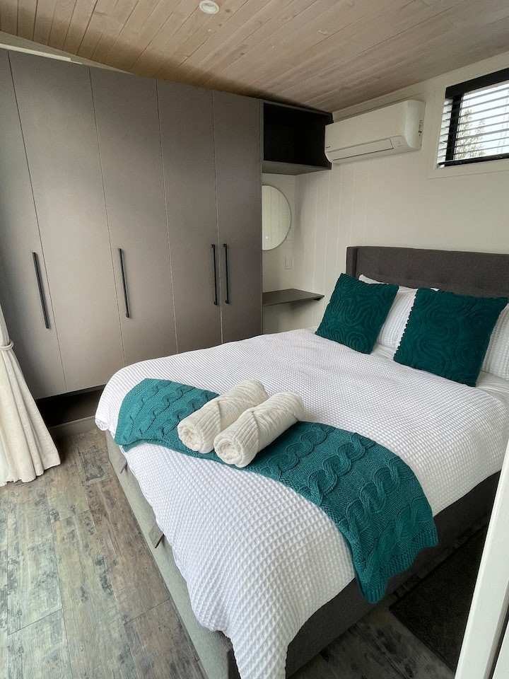 The master bedroom in Tui Lodge has bifold doors that open onto deck with direct access to the bath - the bed lifts up to provide additional storage