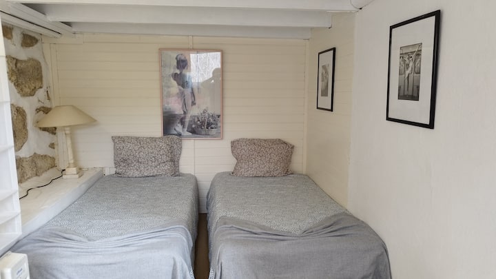 חדר עם שתי מיטות יחיד, במרתף המוגבה של הבית, עם חלון אור ישיר, עם תמונות בנושא בלט, שולחן עבודה והרבה אור טבעי.