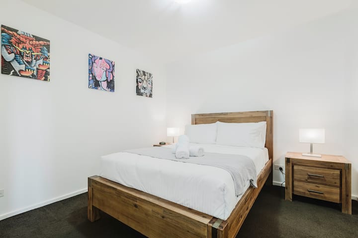 Retiro en el dormitorio: ¡las paredes adornadas con arte y los elegantes muebles de madera crean un escape vibrante!