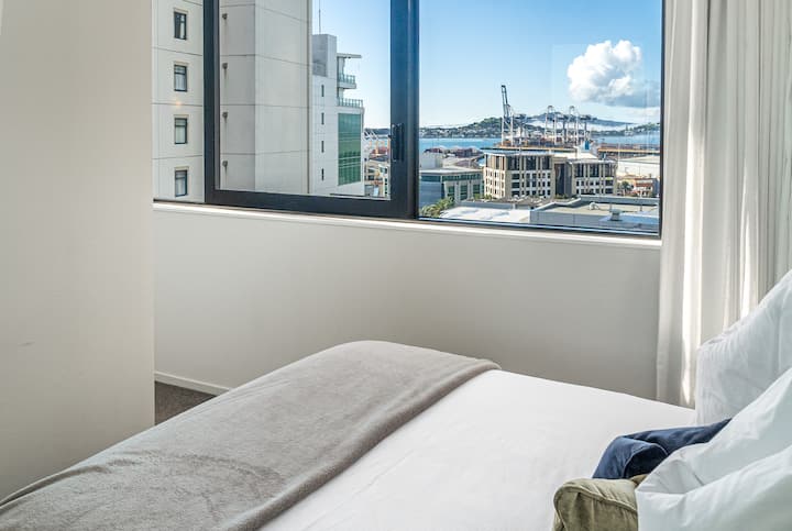 El dormitorio delantero con cama tamaño queen, cajones y un armario, disfruta de las vistas de la isla de Rangitoto y el puerto de Waitemata.