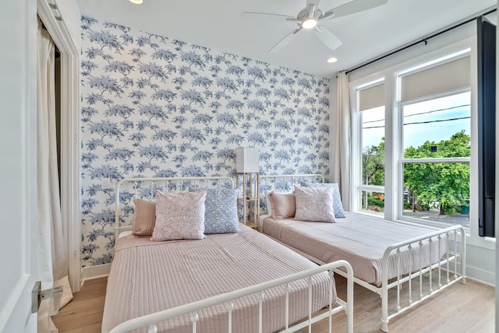 在我们迷人的卧室里休息和充电，两张标准双人床，周围自然光线和绿色植物。