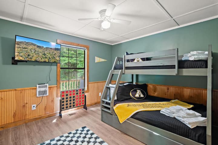 This App State themed bunk room includes a twin over double plus a twin trundle.  Dodatni jastuci, plahte i ručnici u ormaru.  Sjenilo za zamračivanje prostorije održava ga tamnim i tihim za djecu, a oni mogu gledati svoju omiljenu emisiju na TV-u.  