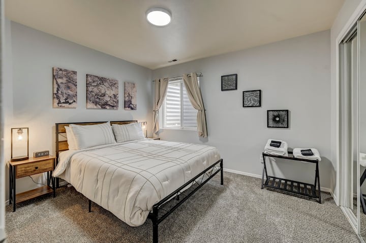 Chumba cha kulala cha chini kilicho na kitanda cha ukubwa wa malkia.  Taa za kando ya kitanda hutoa chaji isiyo na waya kwa vifaa vyako vinavyolingana.