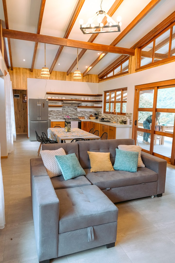 Concepto área abierta:  acogedor espacio con techos altos y grandes ventanales que te regalan mucha luz natural y una hermosa vista de las montañas y el valle. Sala con Smart TV de 50 pulgadas  y un confortable sofá-cama (King-size)