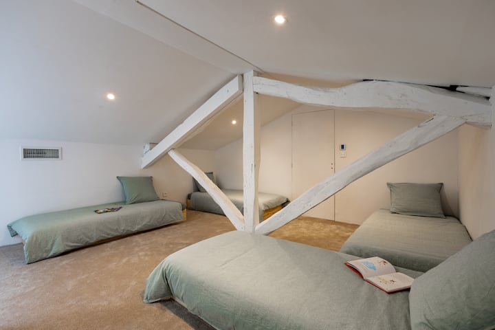 Prostor za spavanje s četiri kreveta i još dva kreveta na drugom kraju sobe.