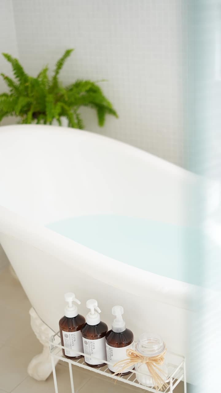 白いタイルに白い猫足バスタブを設えたバスルーム