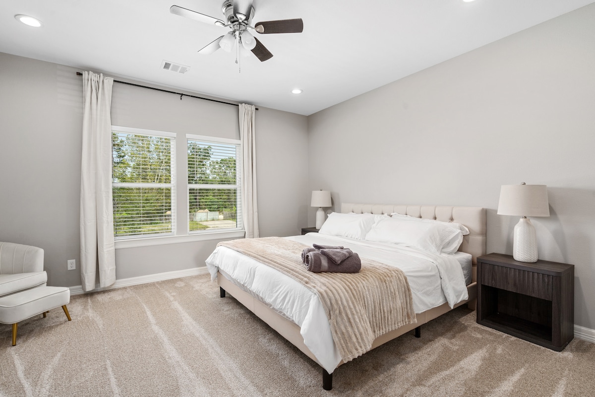 Suita kryesore e dhomës së gjumit. Krevat dopio "king size", karrige me theks dhe perde të errëta. 