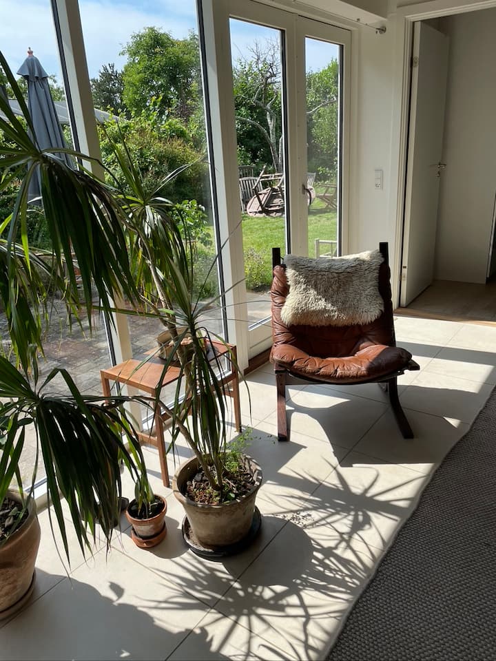 A sala de estar é uma grande sala familiar com luz de grande janela do teto ao chão em ambas as extremidades da sala de estar. Isso dá uma olhada através da casa a partir deste espaço de descanso na sala de estar para o jardim virado para o sul e para a outra extremidade olhando através da parede de vidro voltada para o norte para o lago.