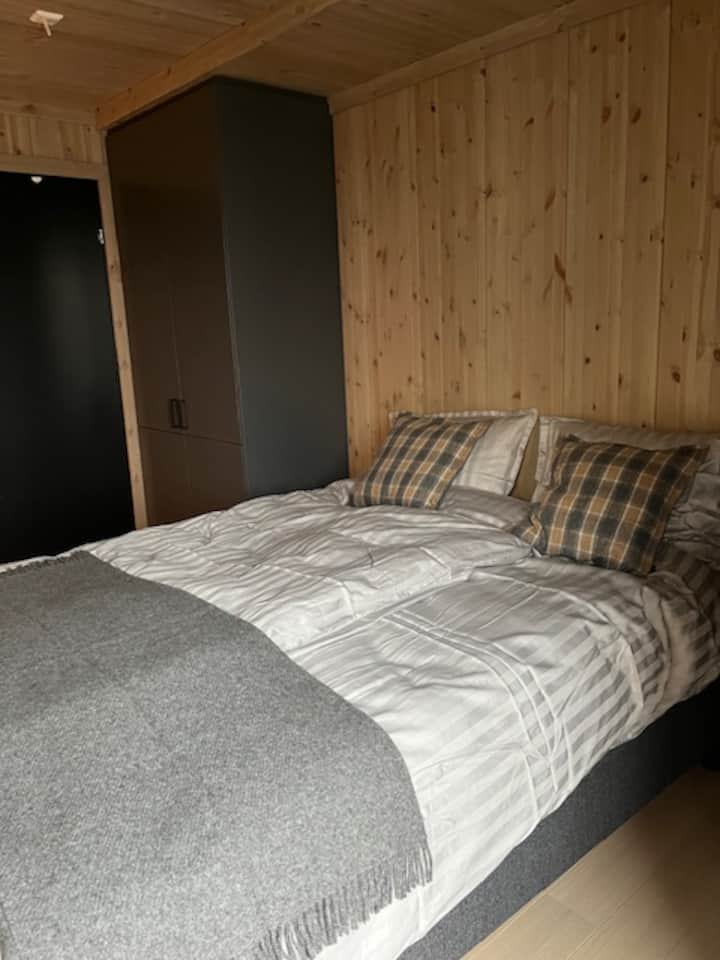 El dormitorio con una cama doble de 160 cm y un armario a ambos lados. En un armario hay un perchero y una aspiradora. 