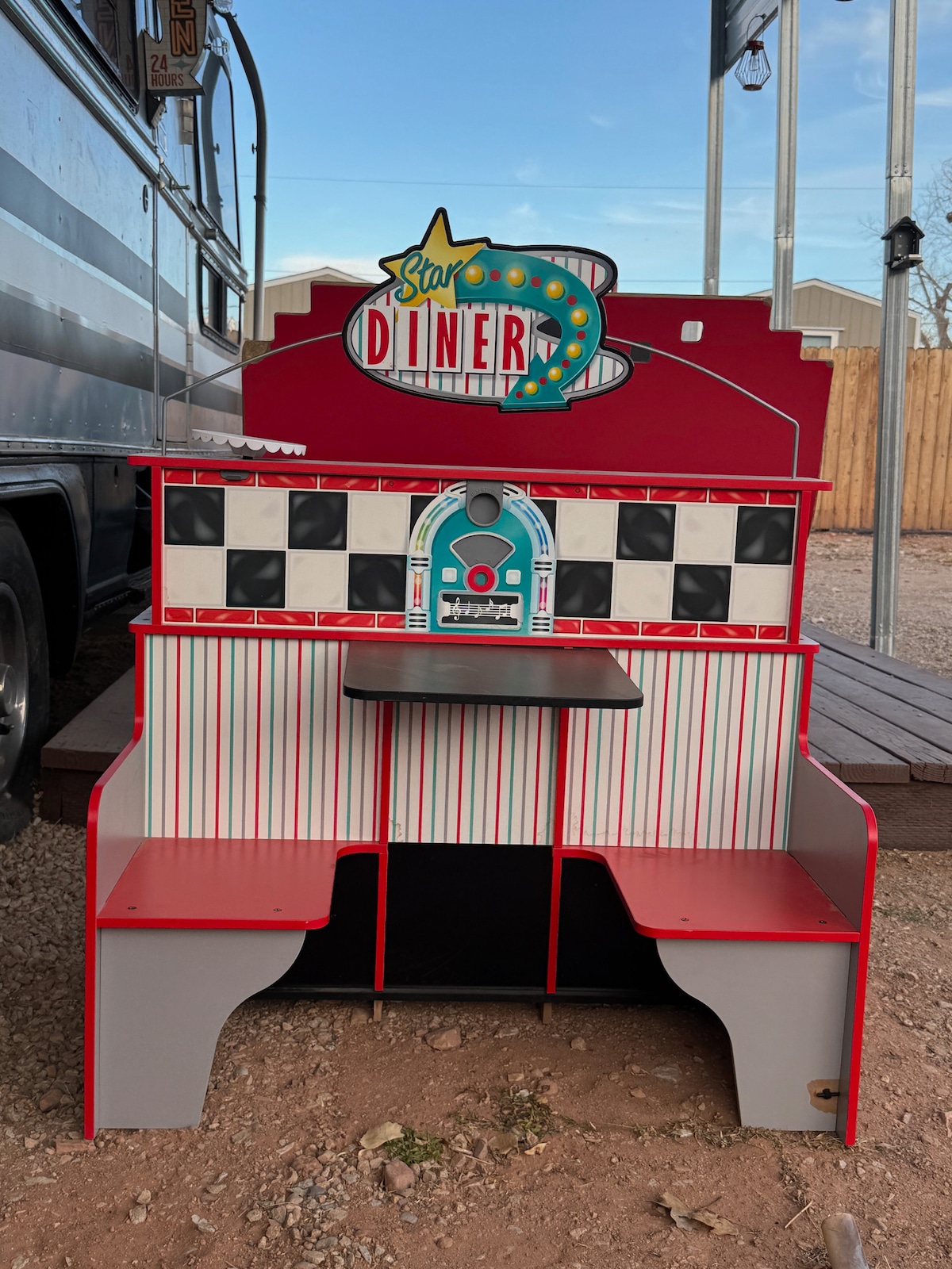 A retro-style diner booth is displayed, featuring bright red accents and a checkerboard pattern. The booth has two spacious seating areas flanking a small table. A colorful sign reading 'Star Diner' is prominently positioned at the top, adding to the fun, nostalgic theme.