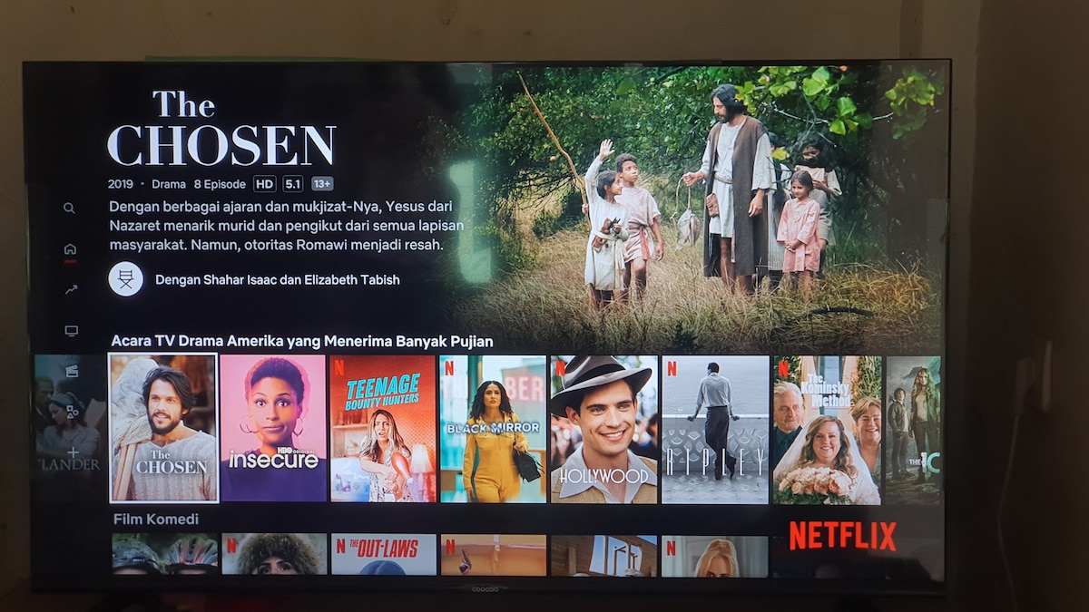 An image of a television displaying a streaming platform interface. The screen features a title card for 'The Chosen' at the top, with a scene from the show presented below. Various shows and movies are shown in organized rows, showcasing genres such as drama and comedy.