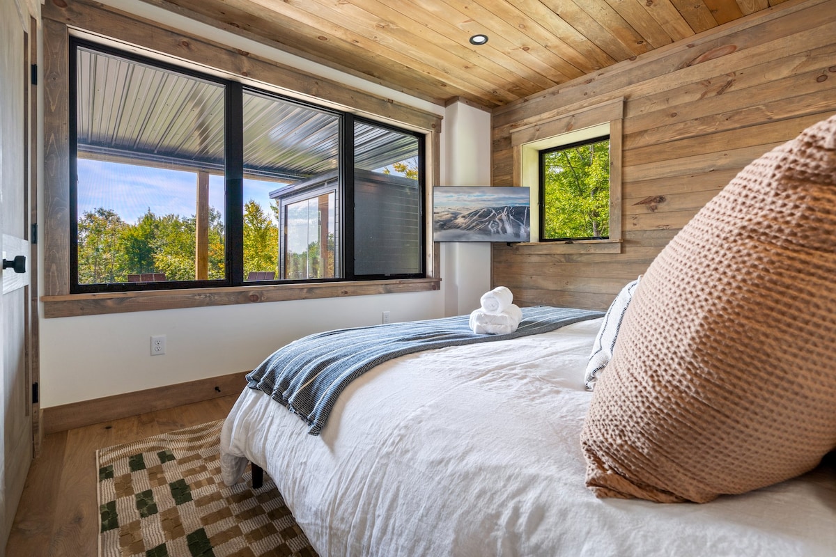 The views of the wood line and backyard add to this luxurious king bedroom with easy access to the lower-level amenities and bathroom