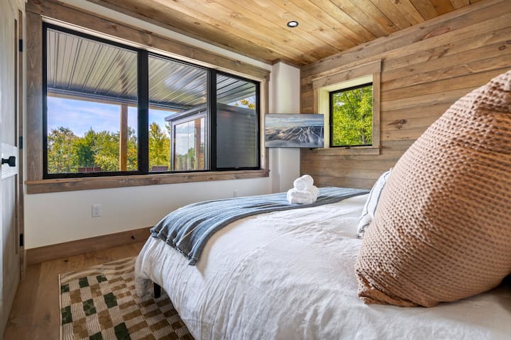 The views of the wood line and backyard add to this luxurious king bedroom with easy access to the lower-level amenities and bathroom