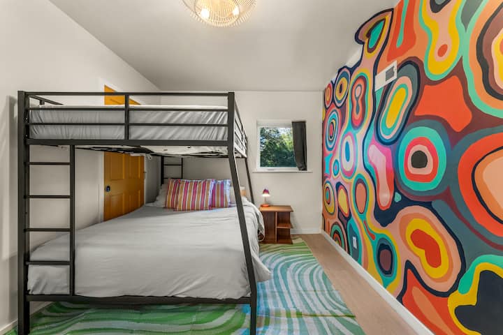 Vivace camera a castello con letto queen-size in basso e letto completo in alto, perfetta per bambini, adolescenti o amici che viaggiano insieme.