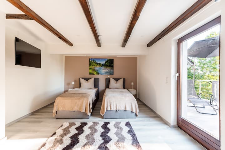 Spacious bedroom with two flexible boxspring beds (also possible as a king size), open wardrobe, 43-inch SMART TV and direct access to the large roof terrace with parasol and two loungers.