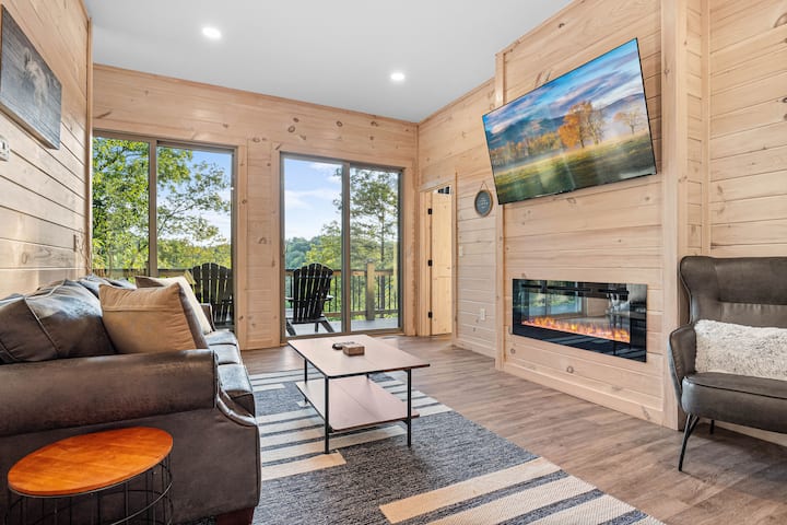 Salon au niveau inférieur avec foyer, téléviseur intelligent et accès à la terrasse – idéal pour se détendre en profitant d'une vue panoramique.