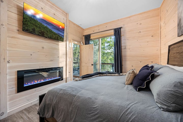 1 des 2 chambres situées au niveau inférieur, lit king size, cheminée électrique, télévision connectée 50 pouces. Portes coulissantes donnant sur la terrasse, avec des sièges juste à l'extérieur de la porte.