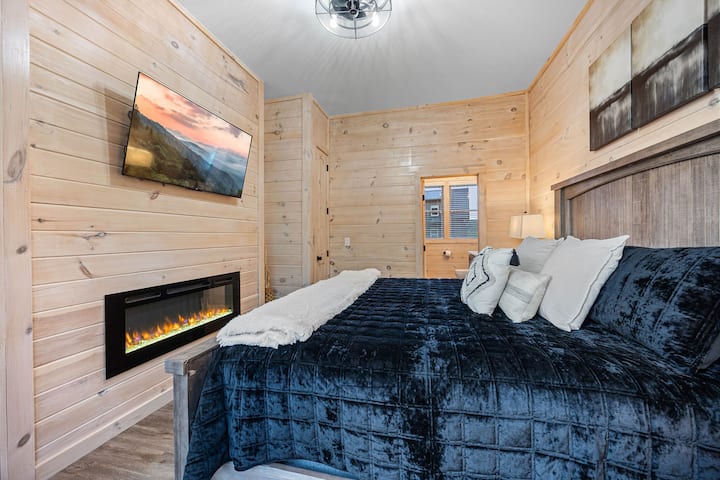 Suite parentale de niveau principal, lit King Size, cheminée électrique, télévision connectée 50 pouces. Des portes coulissantes sur la terrasse, des places assises juste devant la porte.