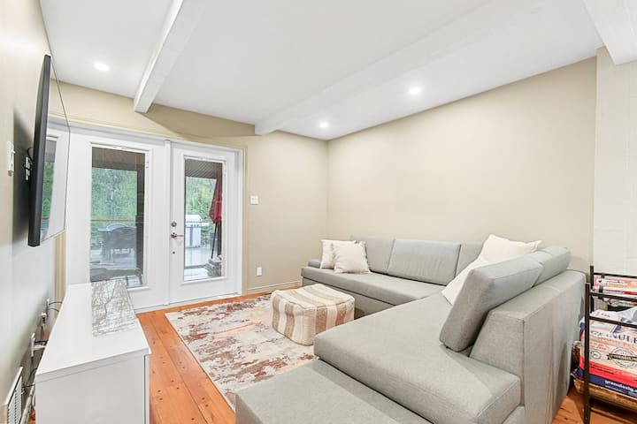 Veľká obývacia izba s manželskou posteľou a kamenným krbom na jednej strane a veľkou pohovkou s rozkladacou pohovkou pre dve osoby a 65-palcovou TV v druhej časti.