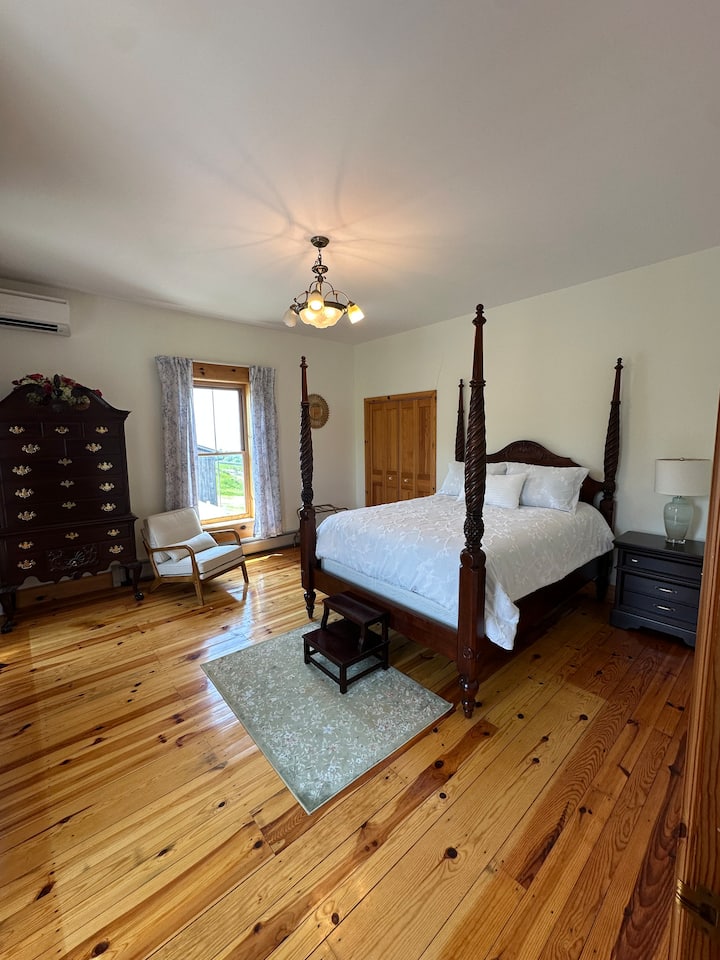 ห้องนอนขนาดใหญ่พร้อมเตียงควีนไซส์ ตู้เสื้อผ้า ชั้นวางกระเป๋าเดินทาง และเก้าอี้