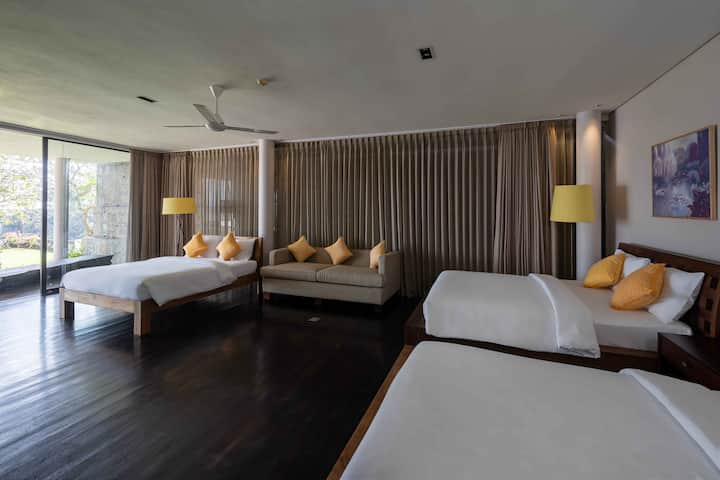 A spacious bedroom featuring three comfortable beds, perfect for accommodating multiple guests or family members. The room also includes a soft sofa, providing a cozy spot for relaxation.