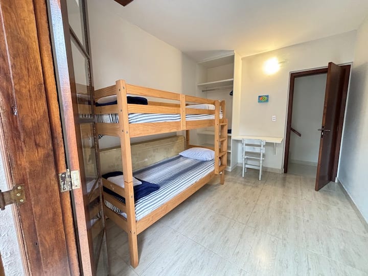Quarto com beliche (2 solteiros), ar condicionado, varanda, local para guardar roupas e local exclusivo para trabalho.
