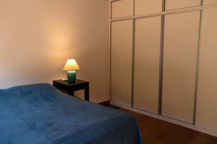 Chambre 1 avec lit double, armoire, tête de lit, lampe, climatisation et vue sur la piscine.