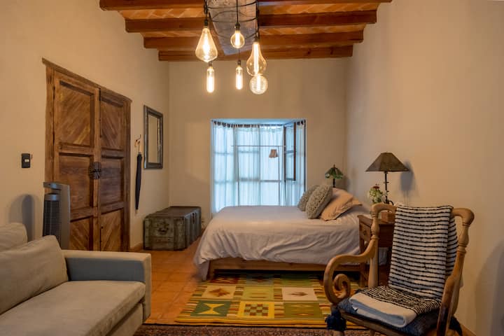 Пространа и удобна спална соба бр. 3 на приземје со брачен кревет, вентилатор, кауч, двојни завеси, телевизор со голем екран и бања пред вратата. 