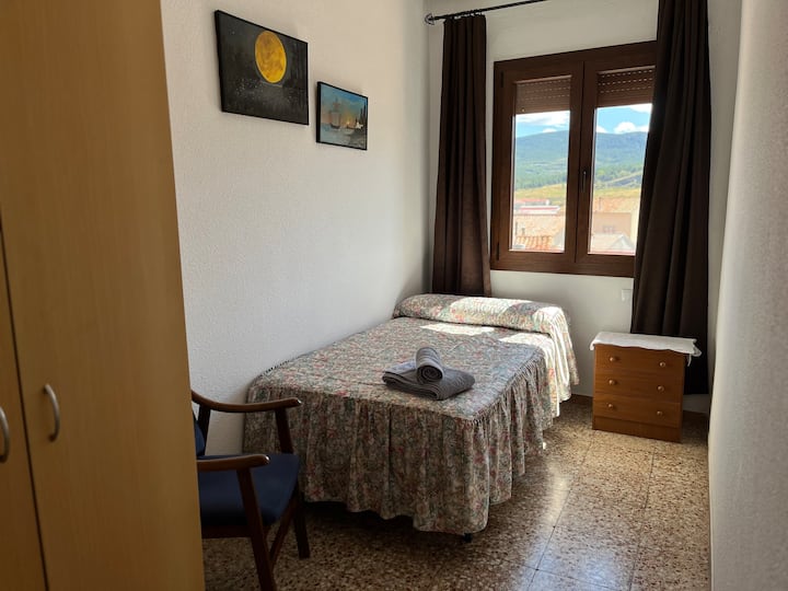 ห้องพักสะดวกสบายพร้อมเตียงเดี่ยว เก้าอี้และตู้ลิ้นชัก หน้าต่างมองเห็นทิวทัศน์ภูเขา พื้นที่ที่เหมาะสำหรับการพักผ่อนในสภาพแวดล้อมที่เงียบสงบด้วยแสงธรรมชาติ