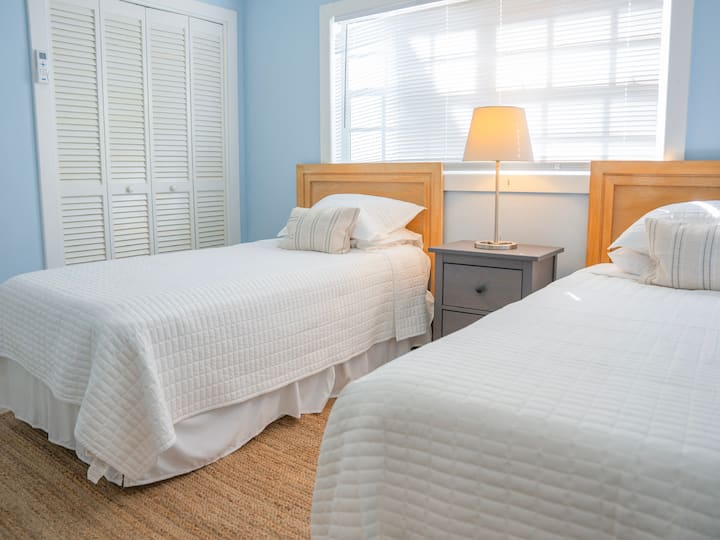 ห้องนอนที่มีแสงสว่างเพียงพอพร้อมเตียงแฝดและทีวี จัดเตรียมไว้อย่างพิถีพิถันเพื่อการเข้าพักที่ผ่อนคลาย