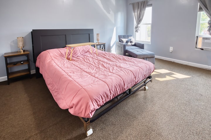 تحتوي غرفة النوم الرئيسية على سرير بحجم كوين، ولوح رأس مع تخزين وطاولتين جانبيتين على الطراز الآسيوي.  نحن نحب مصابيح الطاولة التي تحتوي على منافذ شحن.  أيضًا، اجلس أو استلق على النائم/ كرسي الاستلقاء بينما تستمتع بالتلفزيون الكبير والواي فاي. 