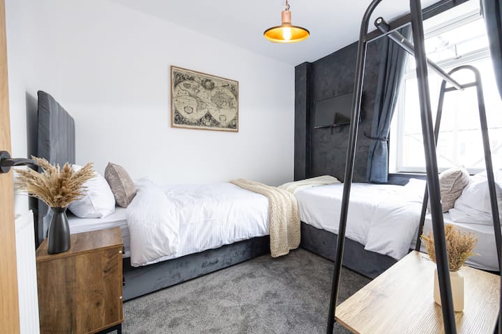 მყუდრო ორადგილიანი საძინებელი ორი ერთადგილიანი საწოლით, რბილი თეთრეულითა და თანამედროვე თბილი დიზაინით.