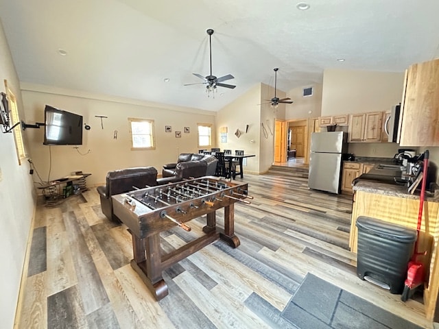 The spacious living area features a foosball table positioned in the center, surrounded by comfortable seating options. A flat-screen television is mounted on the wall, and an adjacent kitchen area is visible, equipped with appliances and dining space.