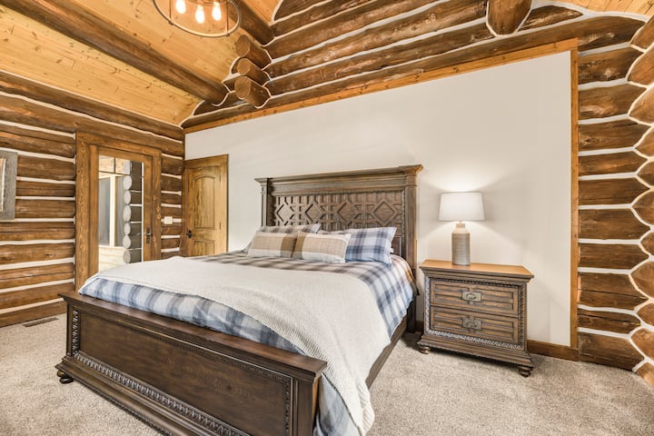 Rilassati in questa accogliente camera da letto in baita, completa di biancheria da letto a quadri, calde finiture in legno e fascino rustico. La luce naturale e l'arredamento classico in stile western creano uno spazio tranquillo e accogliente, perfetto per una notte di sonno riposante dopo una giornata di avventura.