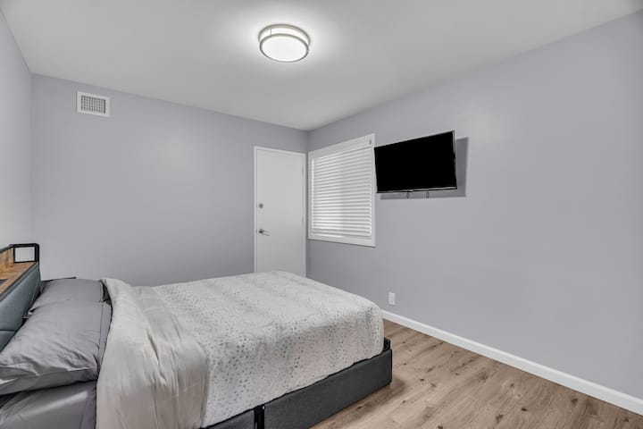 חדר רחצה מודרני עם אמבטיה, שידה וגווני אפור רכים.