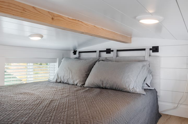 Chambre loft confortable avec un lit Queen Size confortable, une literie douce et des touches chaleureuses de bois naturel. Cet espace de couchage surélevé offre une retraite paisible avec de la lumière naturelle et un design de micro-maison moderne, parfait pour se détendre après des journées riches en aventures.