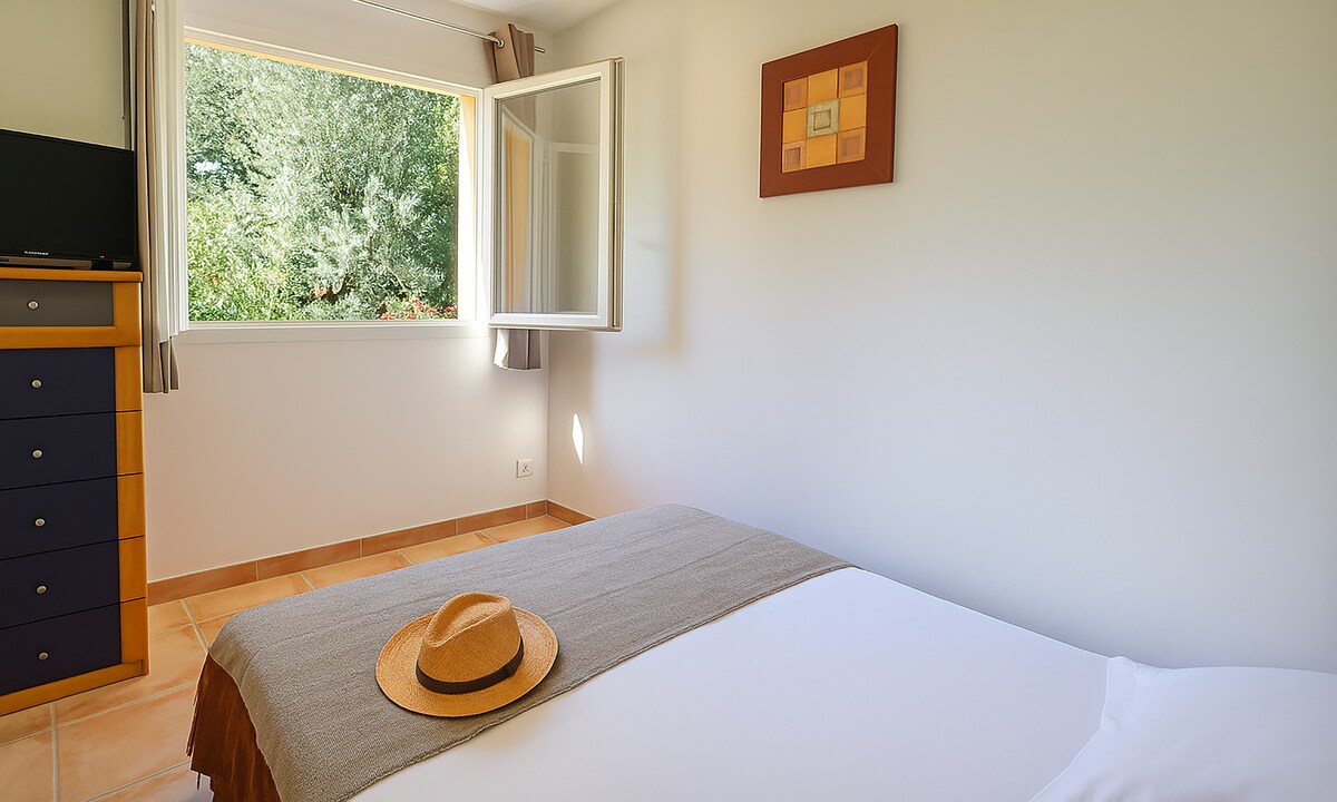 غرفة نوم تطل على أشجار الزيتون ، مع إمكانية وضع سرير أطفال في غرفة النوم.