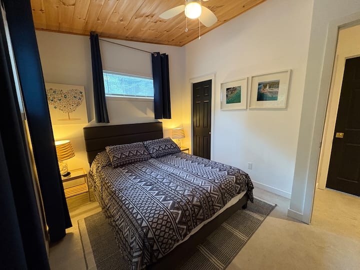 Queen size bed, tv, room darkening curtains, ceiling fan, clothing storage, knotty pine high sloped ceiling
