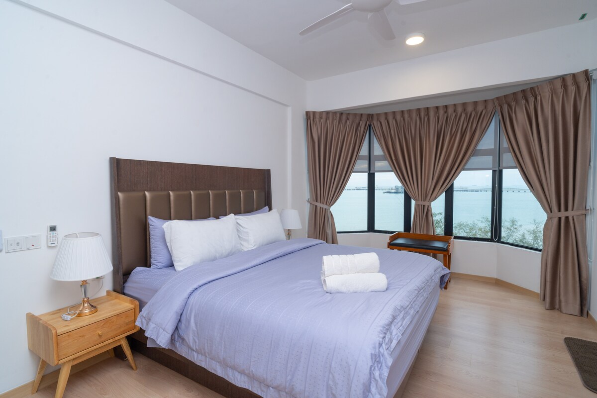 Spálňa 1 (8. poschodie) má manželskú posteľ s fialovou posteľnou bielizňou, plyšovými vankúšmi a elegantným polstrovaným čelom. Široké arkýřové okno s nádherným výhľadom na more orámované celoplošnými závesmi - ideálny priestor na oddych a načerpanie nových síl.
